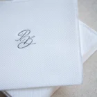 Servilleta blanca con monograma elegante sobre fondo beige